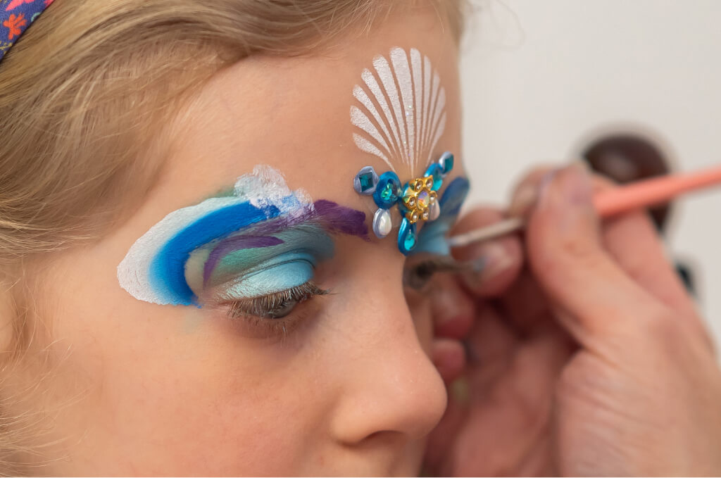 Kék és fehér díszes arcfestés készítése gyerek arcon