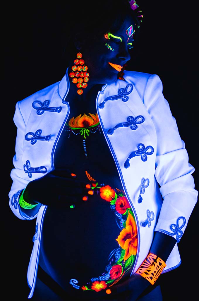 UV pocakfestés virágmintával fekete fényben várandós pocakon